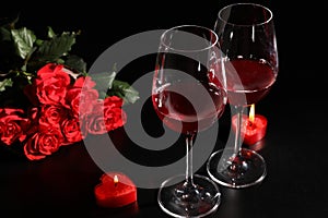 Glasses of wine, roses and heart shaped candles for romantic dinner on table