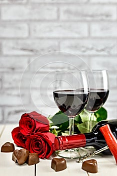 A glasses of wine, wine bottle, roses and chocolate hearts