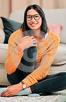 Glasses, woman and smile in portrait with winter fashion, warmth and comfort on floor in living room. Female person