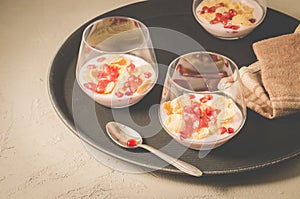 glasses with yogurt with pomegranate and flakes on a black tray/glasses with yogurt with pomegranate and flakes on a black tray on