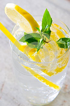 The glasss of mojito with lemon and drinking straw