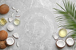 Glassware with natural organic oil and coconuts on grey stone background, flat lay