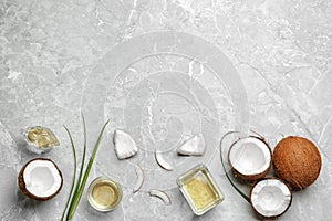 Glassware with natural organic oil and coconuts on grey stone background, flat lay