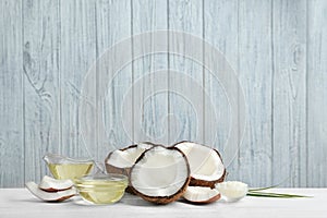 Glassware with natural organic oil and coconuts on white wooden table