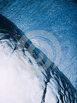Glassy surfung wave underwater in transparent blue water