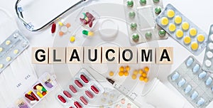 GLAUCOMA medicine word on wooden blocks on a desk. Medical concept with pills, vitamins, stethoscope and syringe on the background