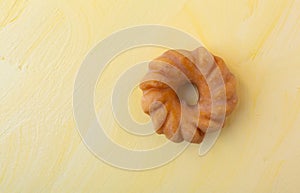 Glazed cruller on a yellow background