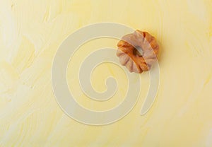 Glazed cruller on a yellow background