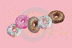 Glazed doughnuts in motion falling on pink background with colorful sprinkles