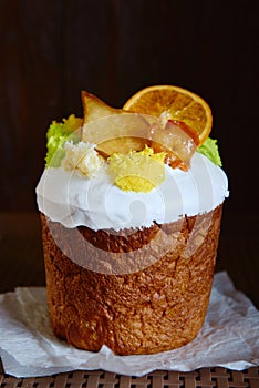 Glazed easter cake decorated with dried orange and pear slices on dark background, copy space. Happy Easter holidays. Kulich