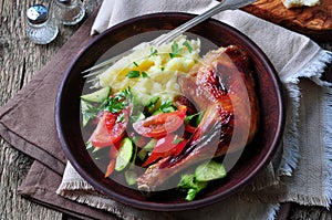 Glazed roasted chicken leg with mashed potatoes and vegetable salad on a wooden background