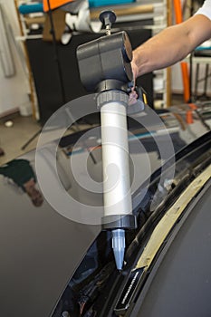 Glazier with application gun applying adhesive for windshield replacement