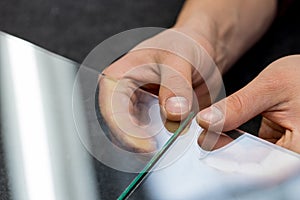 The glazier breaks the glass in his fingers