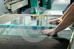 Glazier cuts and breaks glass on a professional table in the workplace