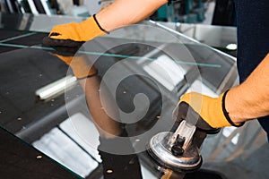 A glazier in a glass factory removes heavy glass using suction cups, specialized industrial tools