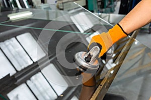 A glazier in a glass factory removes heavy glass using suction cups, specialized industrial tools