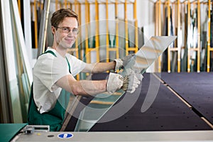 Glazier handling piece of glass in workshop