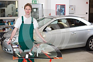 Glazier handling windscreen in garage