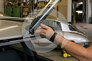 Glazier using application gun to apply adhesive for windscreen