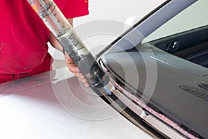 Glazier using application gun to apply adhesive for windscreen