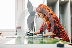 Glazier woman worker cutting glass in workshop.