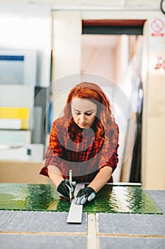 Glazier woman worker cutting glass in workshop. Industry