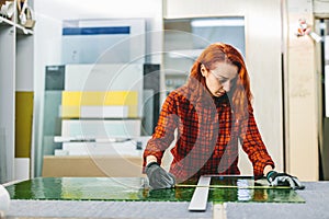 Glazier woman worker measuring glass in workshop. Industry