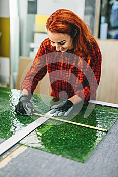 Glazier woman worker measuring glass in workshop. Industry