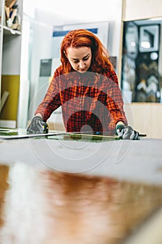 Glazier woman worker measuring glass in workshop. Industry