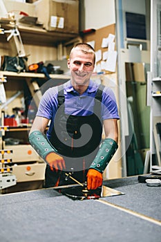 Glazier worker cutting glass with compass glass cutter in a workshop