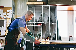 Glazier worker cutting glass with fire in a workshop