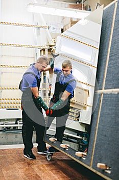 Glazier worker holding a big mirror glass pane in workshop.