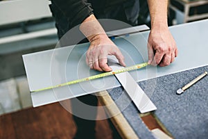 Glazier worker measuring glass in workshop. Industry