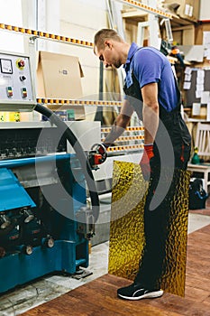 Glazier worker operates glass cutting machine in workshop