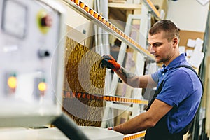 Glazier worker operates glass cutting machine in workshop