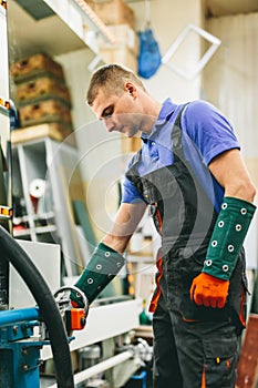 Glazier worker operates glass cutting machine in workshop