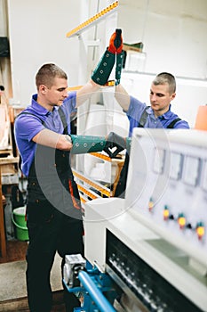 Glazier worker operates mirror glass cutting machine in workshop