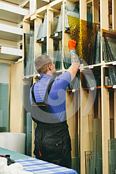 Glazier worker picking glass pane in workshop. Industry