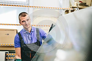 Glazier worker portrait with glass in workshop.