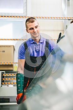 Glazier worker portrait with glass in workshop.