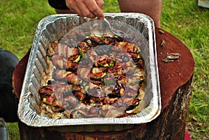 Glazing cooked bacon wrapped stuffed jalapenos at a cookout