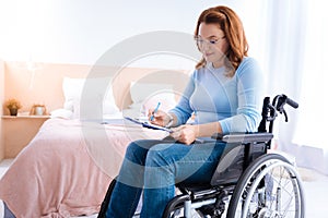 Gleeful crippled woman writing on a sheet of paper