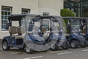 Blue golf buggies parked up in a row at the golf course