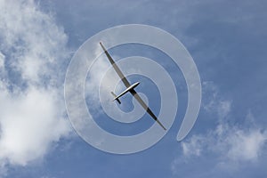 Glider against blue cloudy sky. Single seat high performance sailplane