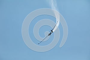 A glider flying in the blue sky ejects the water before the landing.