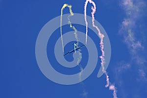 Glider performing aerobatics with smoke trails at airshow