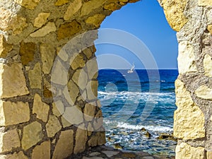 A glimpse of the Mediterranean framed by an arch in  sea wall of Chania harbour, Crete on a bright sunny day