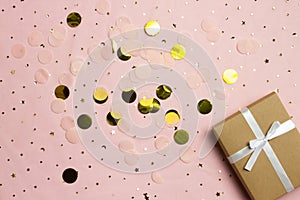Glitter background with gift box. Golden stars in the form of confetti on pink background.