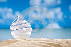 Glitter christmas glass ball on beach with seascape