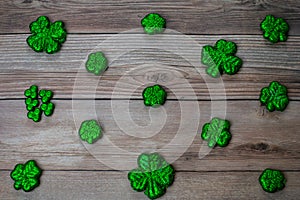 Glitter Covered Four Leaf Clovers in a Pattern on a Wood Background